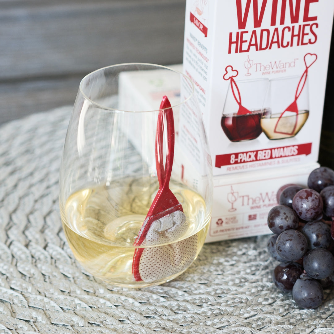 Wine glass with a red wine swab, box of wine swabs, and grapes on a textured surface.
