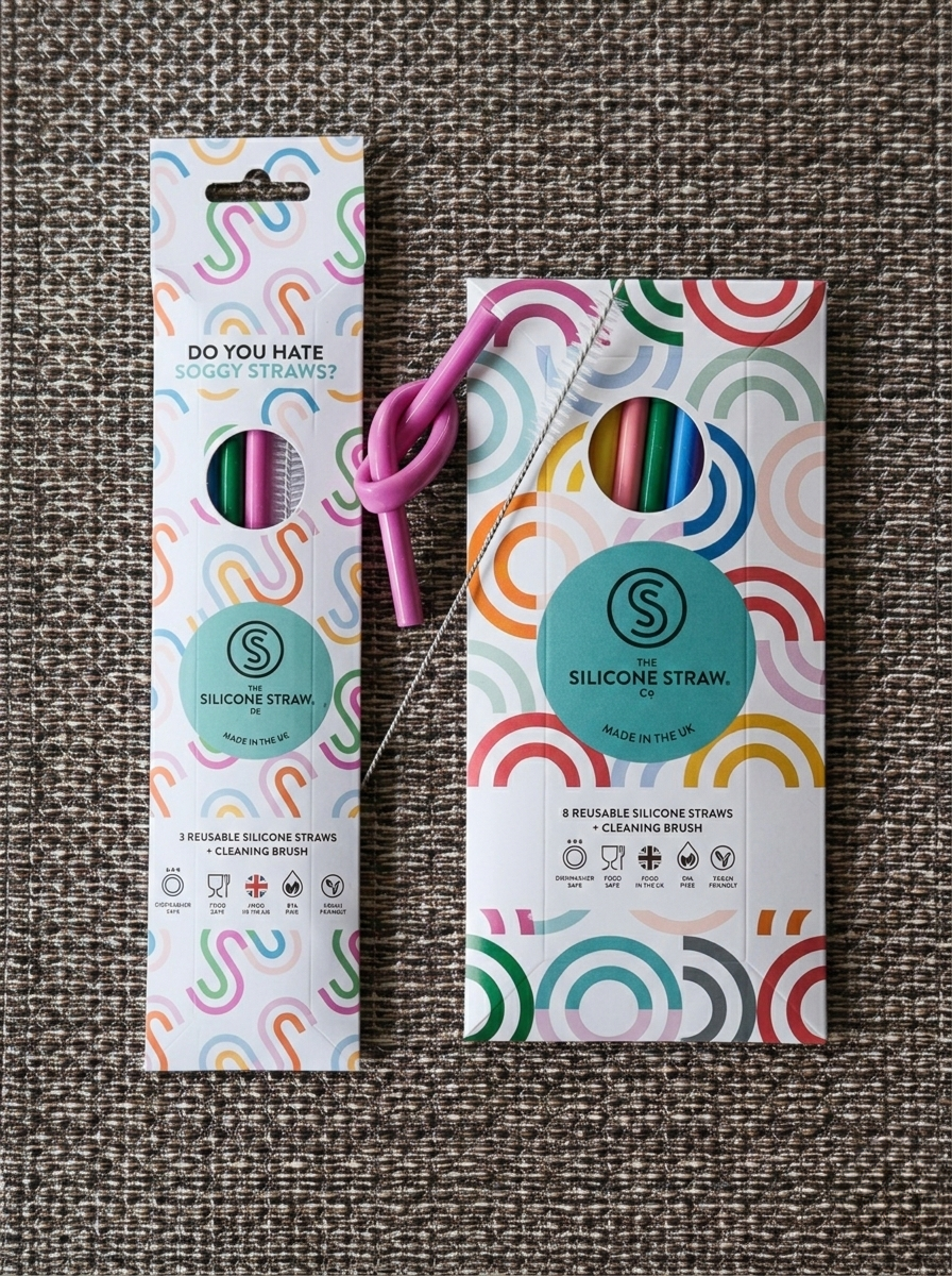 Two silicone straw packages with colorful designs on a textured surface