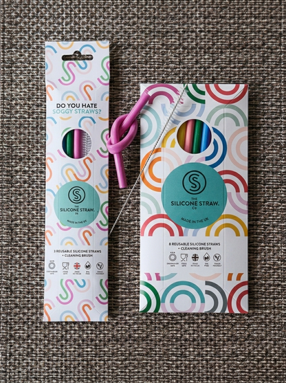 Two silicone straw packages with colorful designs on a textured surface