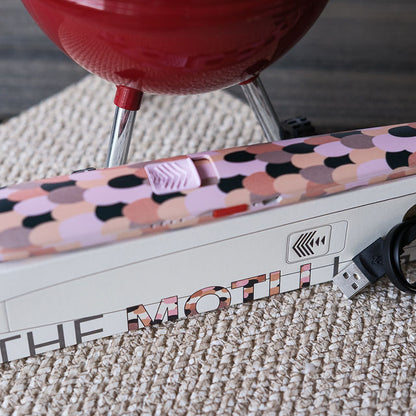 Close-up of a colorful USB device with 'The Moth' branding on a textured surface.