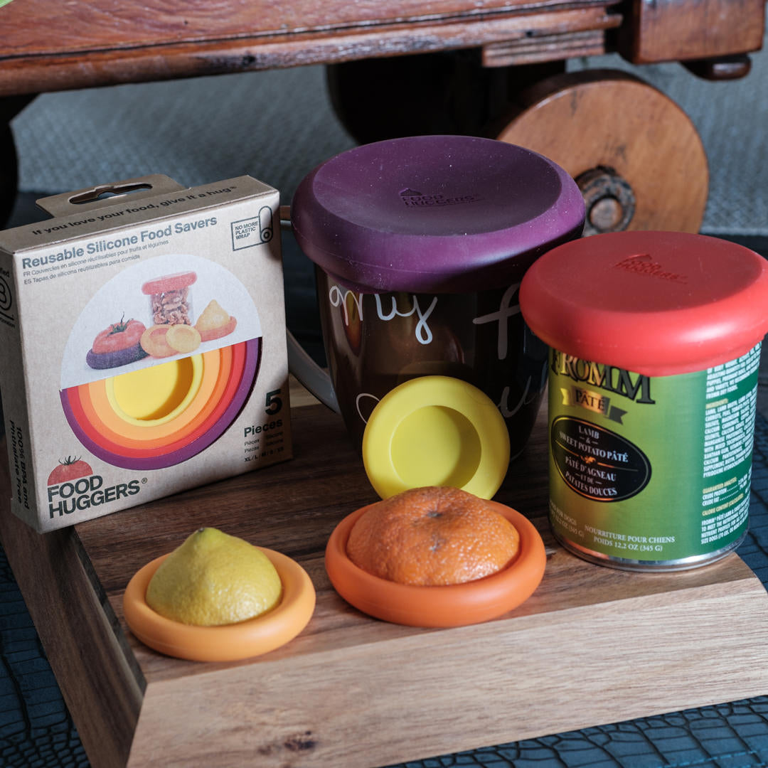 Reusable silicone food savers with containers on a wooden surface