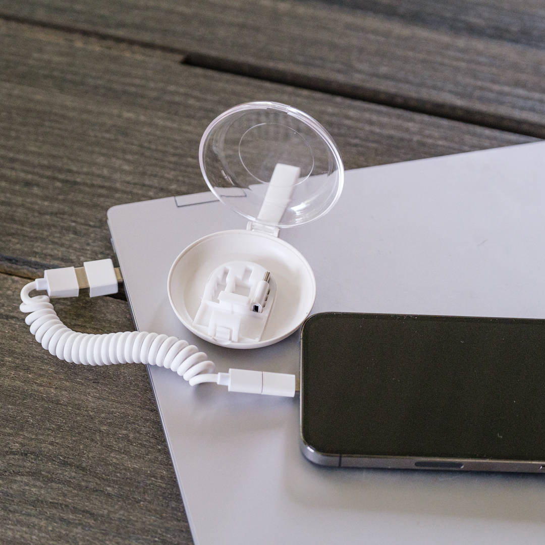 White electronic device with coiled cable on a wooden surface
