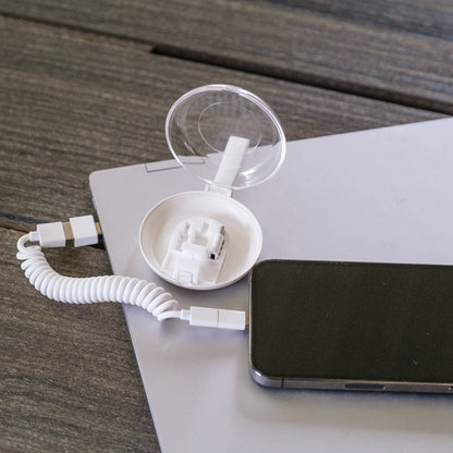 White electronic device with coiled cable on a wooden surface