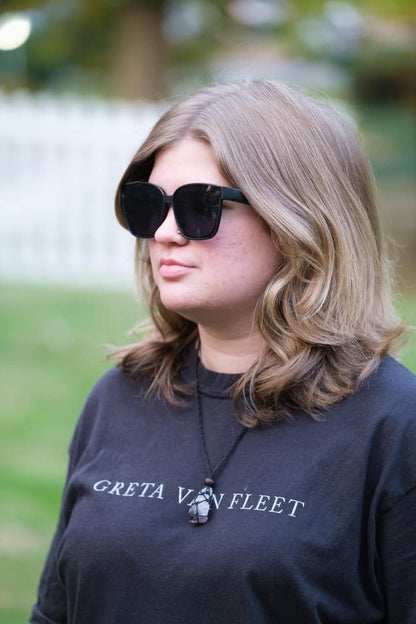 Person wearing sunglasses and a black 'Greta Van Fleet' shirt outdoors