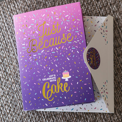 Purple card with gold text 'Just Because Let's Celebrate with Cake' on a textured surface