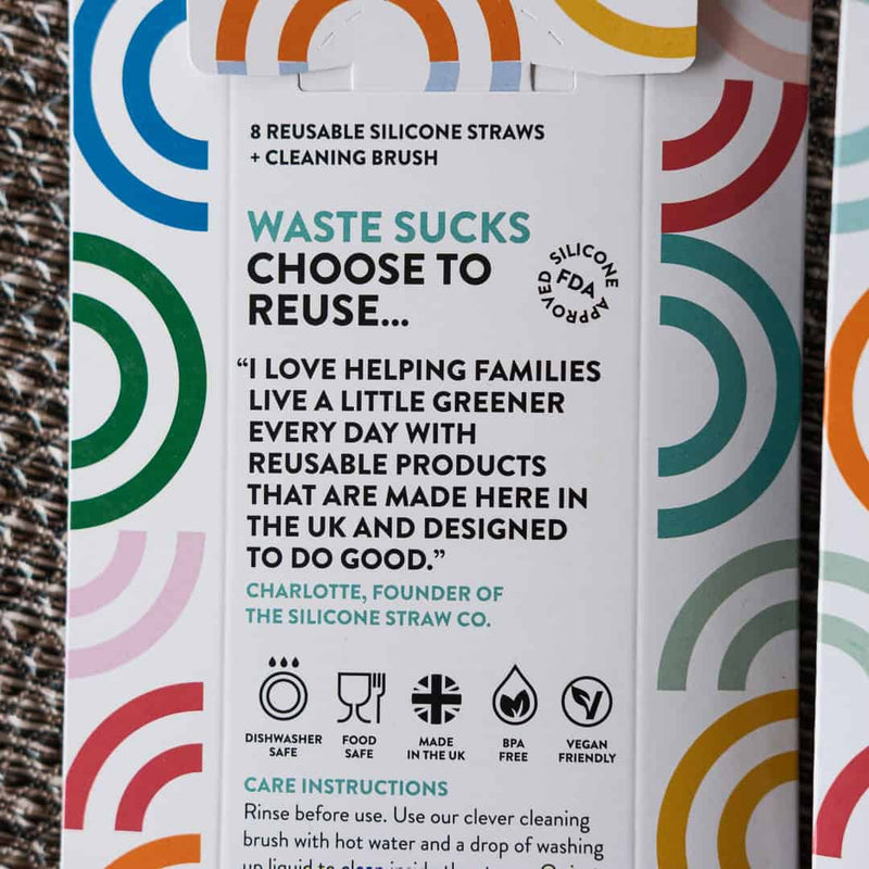 Packaging of reusable silicone straws with colorful design and text on a textured surface.