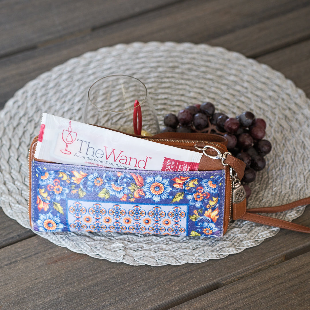 Floral-patterned wallet with 'The Wand' magazine on a woven mat