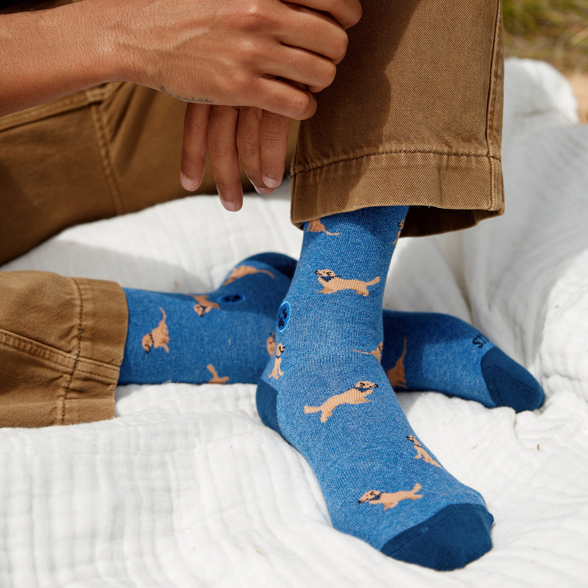 Person wearing blue socks with dog pattern on a white blanket